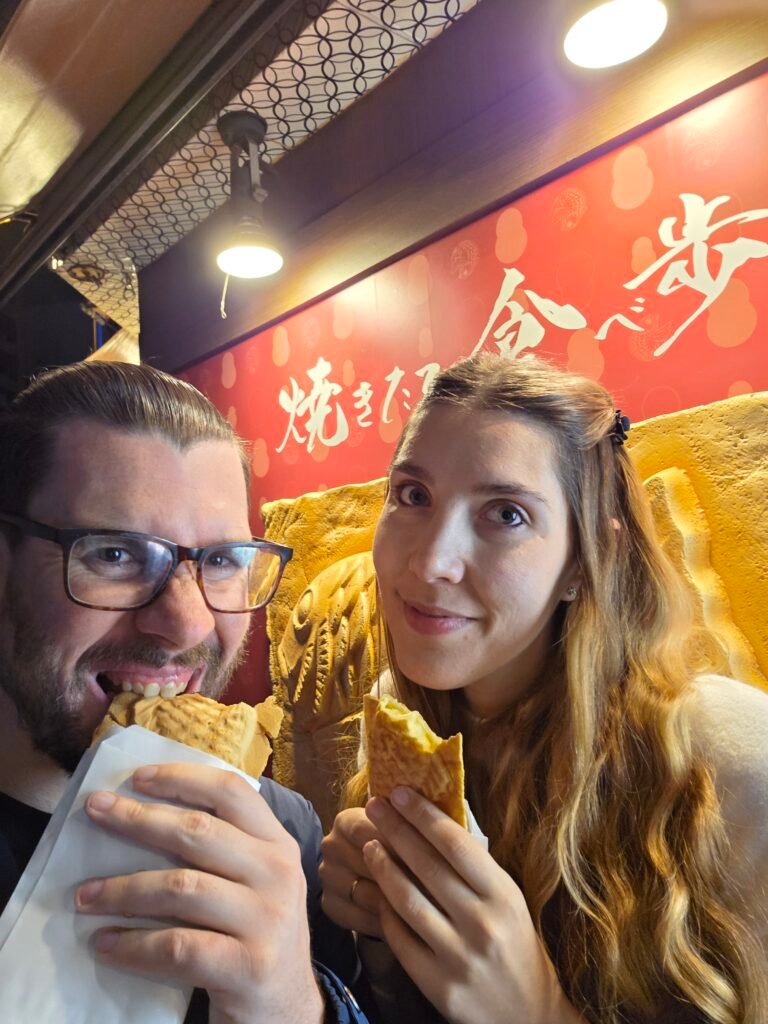 IATI Seguros: ¿El mejor seguro de viaje para Japón? Nuestra opinión real y experiencia Carlos y Sonia buscando el mejor seguro de viaje a Japón comiendo Taiyaki