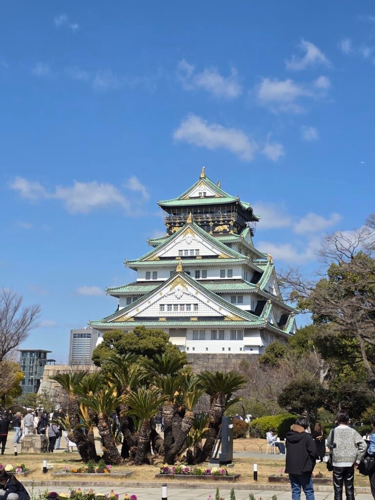 Vista exterior majestuosa de el Castillo de Osaka rodeado de árboles y el foso de agua
